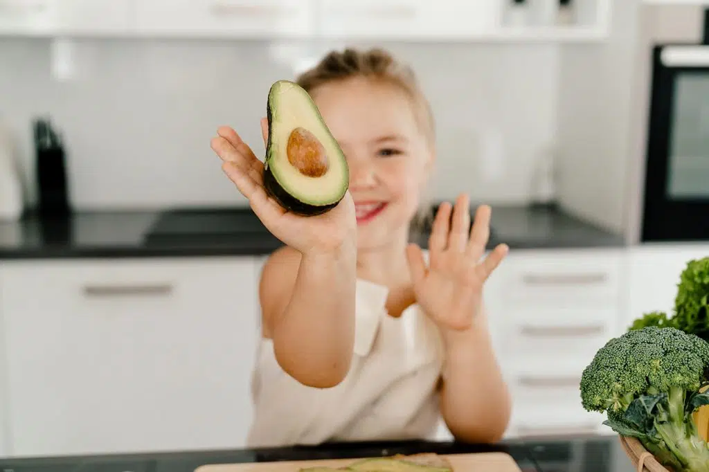 Kind hält Avocado in die Kamera