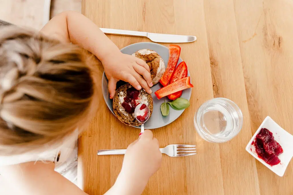Foto vegane Kinderernährung - Kind sitzt am Tisch und frühstückt